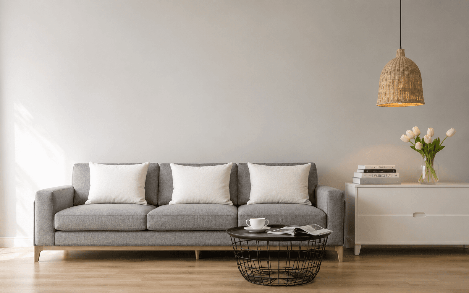 Grey three-seat sofa with white cushions in a bright, minimally furnished living room